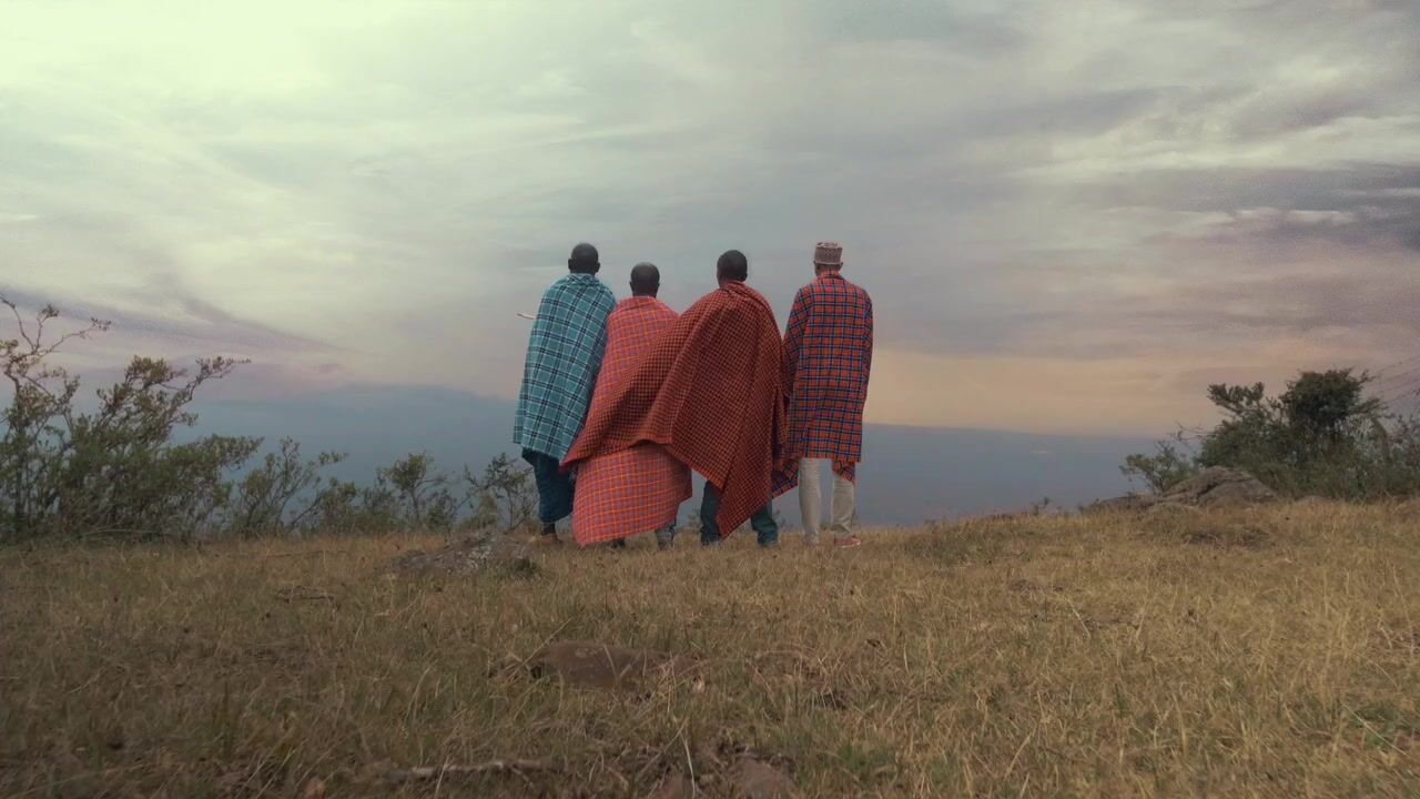 a group of people standing on top of a grass covered hill